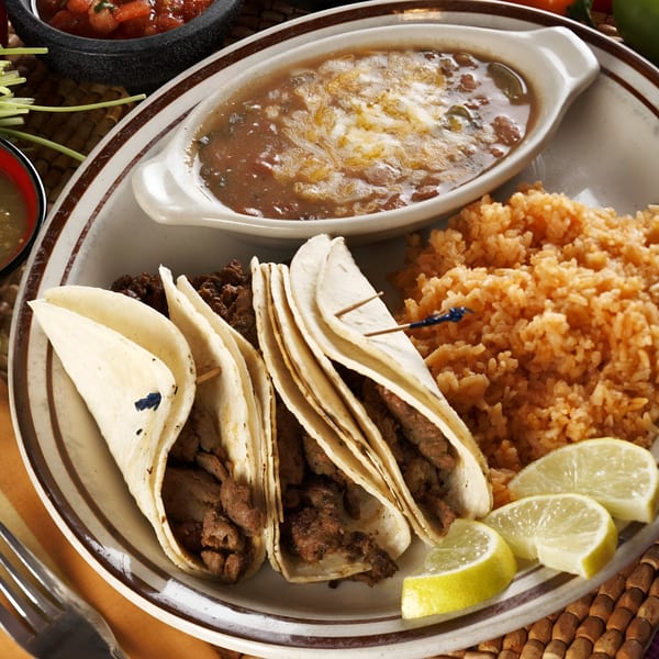 Manuel's El Burrito's plate with three street tacos, rice, beans, and lime wedges.