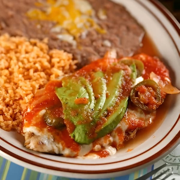 Manuel's El Burrito's Mexican dish with rice, refried beans, and a main course topped with avocado and salsa.