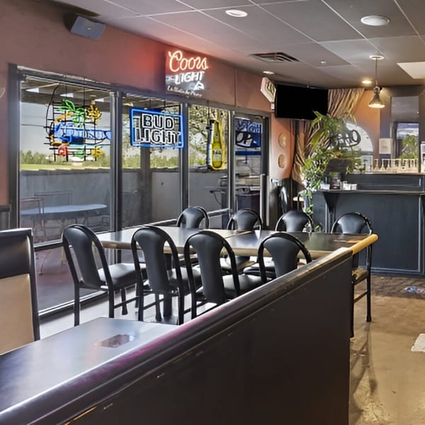 Interior of Manuel's El Burrito Restaurant & Cantina with tables, chairs, and neon beer signs.