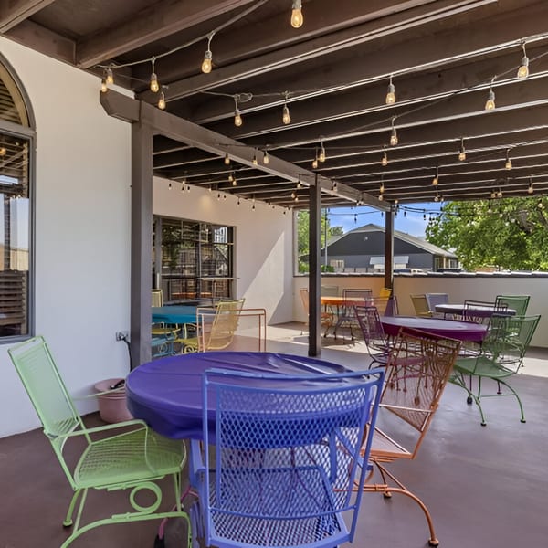 Outdoor patio at Manuel's El Burrito with colorful tables and chairs under string lights.
