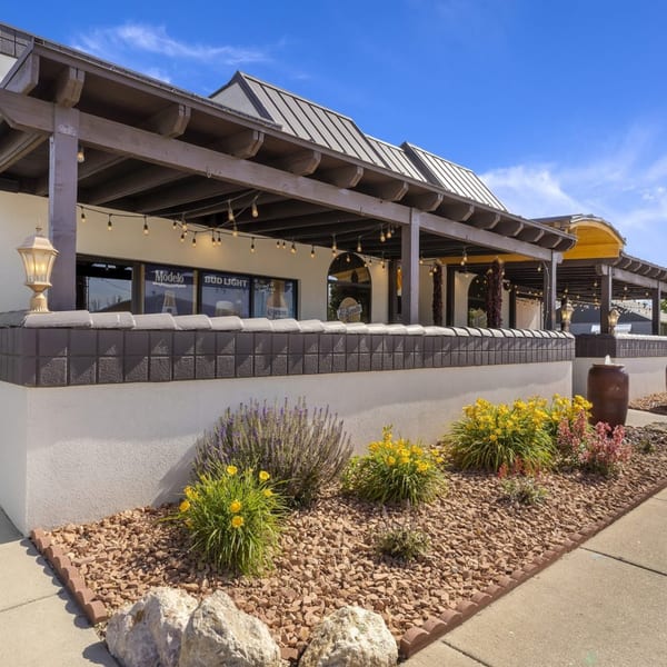 Exterior of Manuel's El Burrito Restaurant & Cantina, featuring a covered patio with string lights and landscaping.