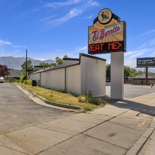 Manuel's El Burrito Restaurant & Cantina's outdoor sign with "GREAT MEX" in red letters, mountains in background.