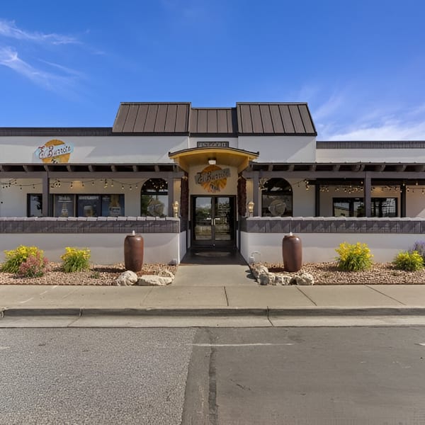 Exterior of Manuel's El Burrito Restaurant & Cantina, a white building with a brown roof and patio.