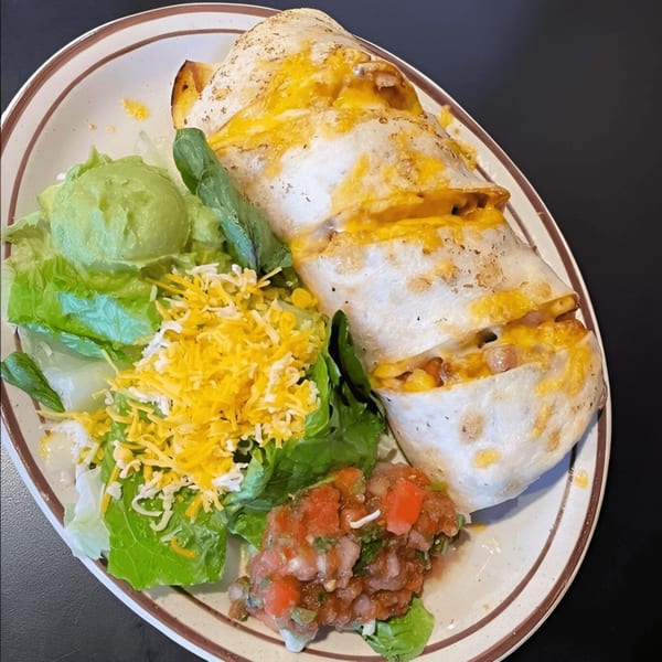 Manuel's El Burrito's cheesy burrito with a side of guacamole, salsa, and shredded lettuce.
